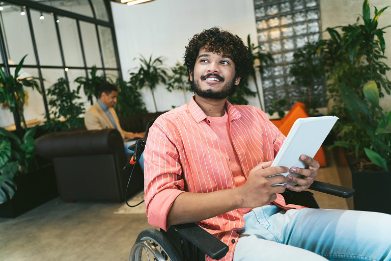 A wheelchair user in an office holding a tablet device